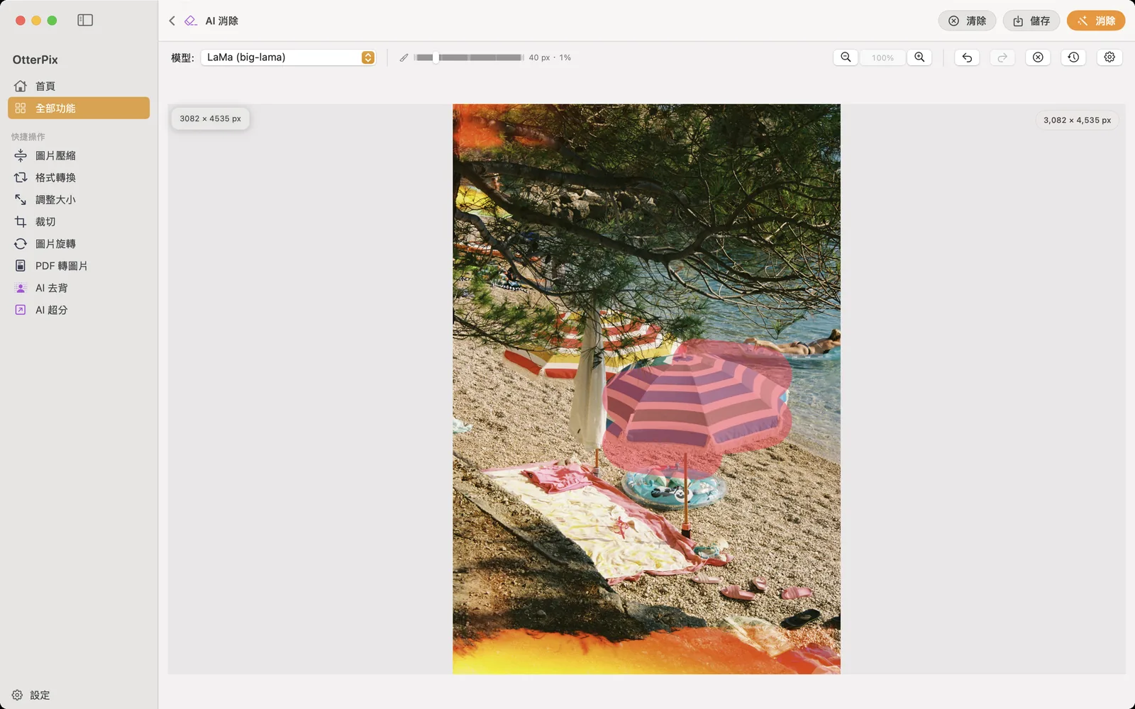 macOS 上的 OtterPix AI 消除工具:沙灘相片裡的條紋遮陽傘已用紅色筆刷塗抹標記,工具列右上角是「消除」按鈕。